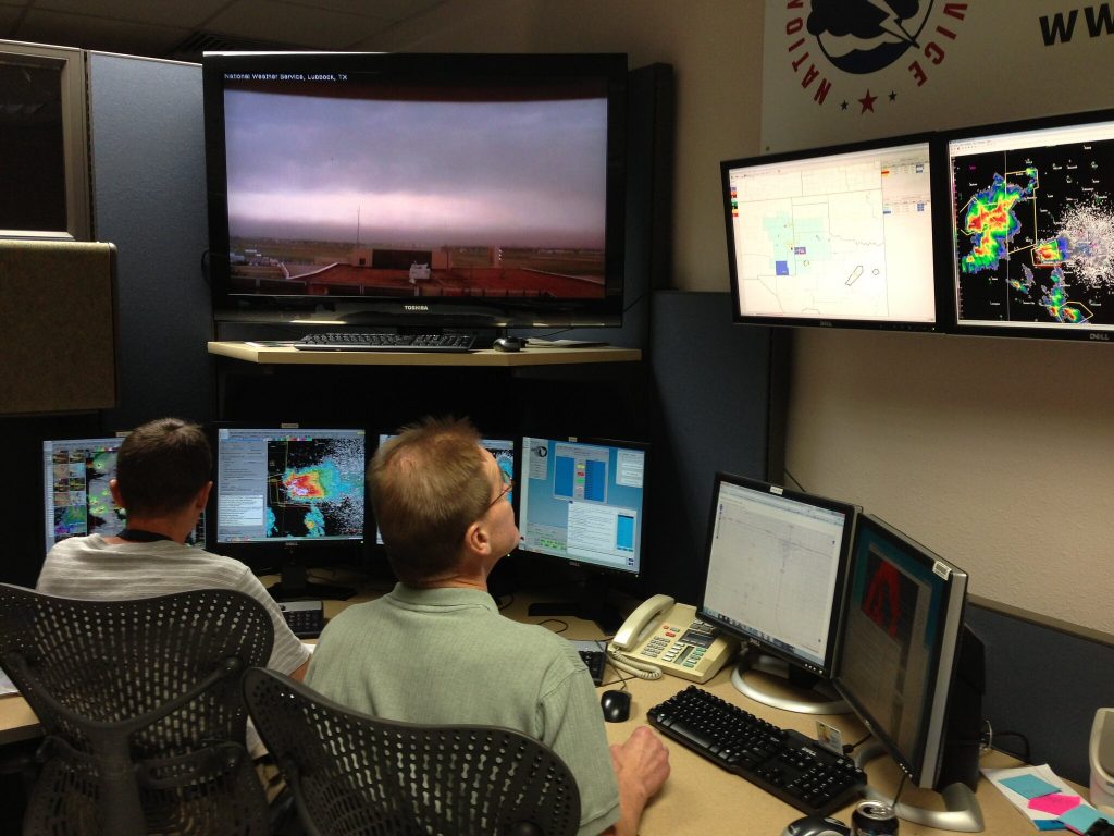 Government employees monitoring evolving weather conditions on a variety of computer systems