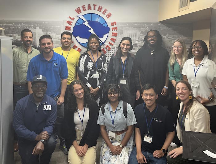 A group of individuals standing in front of a National Weather Service banner.