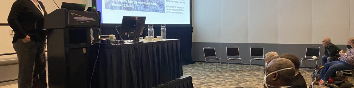 Dr. Maoyi Huang presenting during the EPIC Town Hall with Dr.'s Neil Jacobs (left) and Michael Morgan (right) watching from the audience.